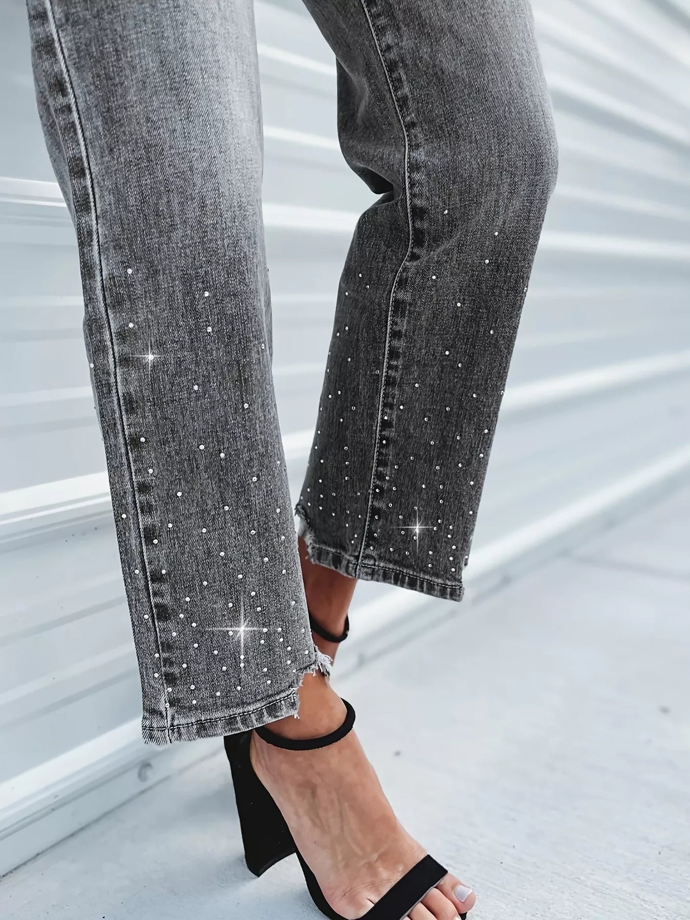 Close-up of gray jeans with sparkling embellishments on a light background
