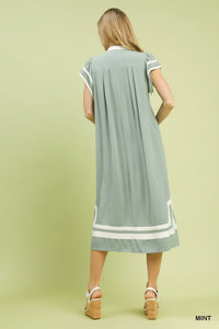 Woman wearing a light green dress with white accents on a solid background