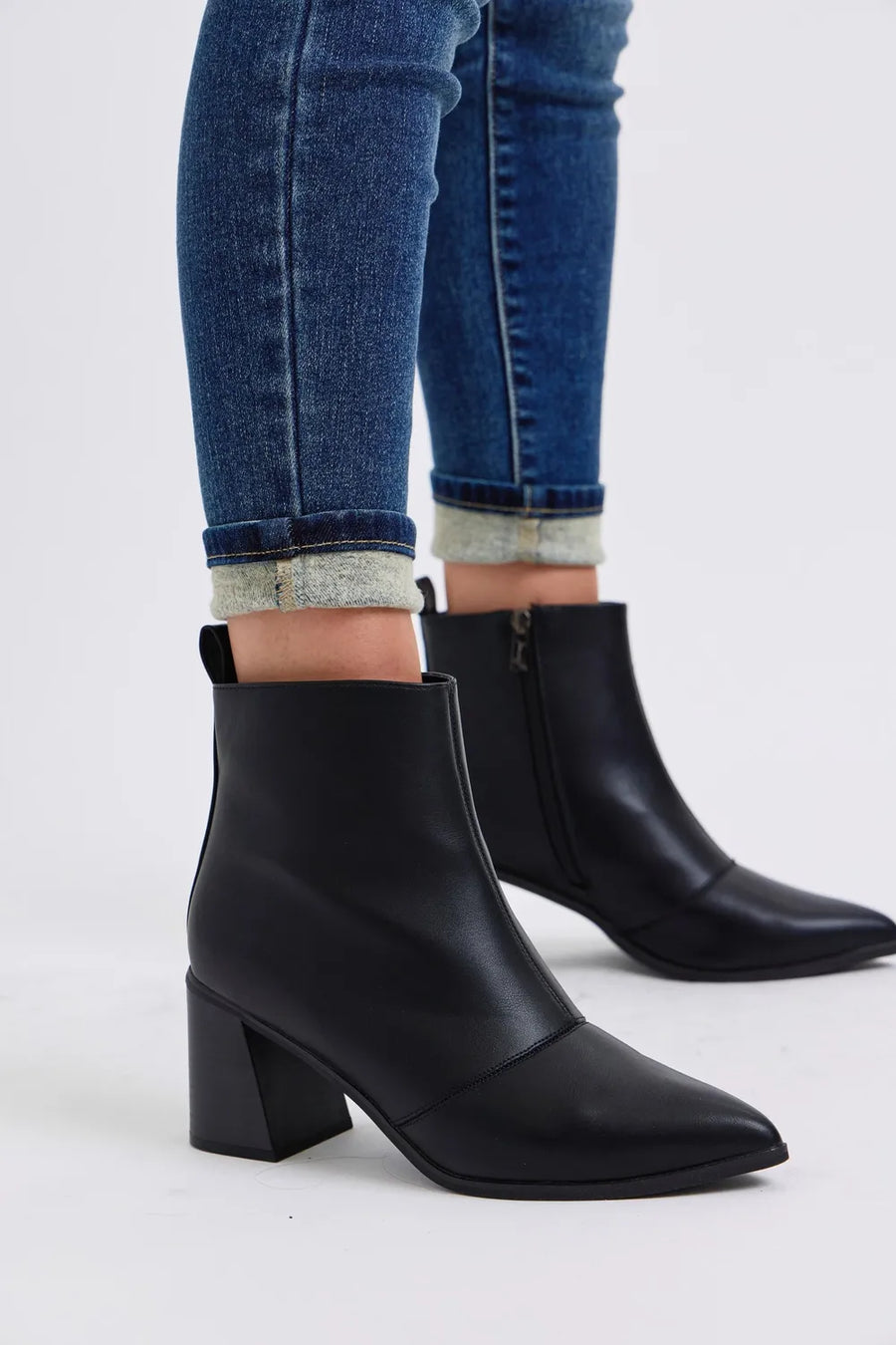 Black ankle boots worn with blue jeans on a white background