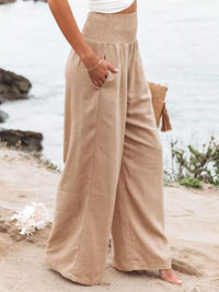 Person wearing beige wide-leg pants standing on a beach.