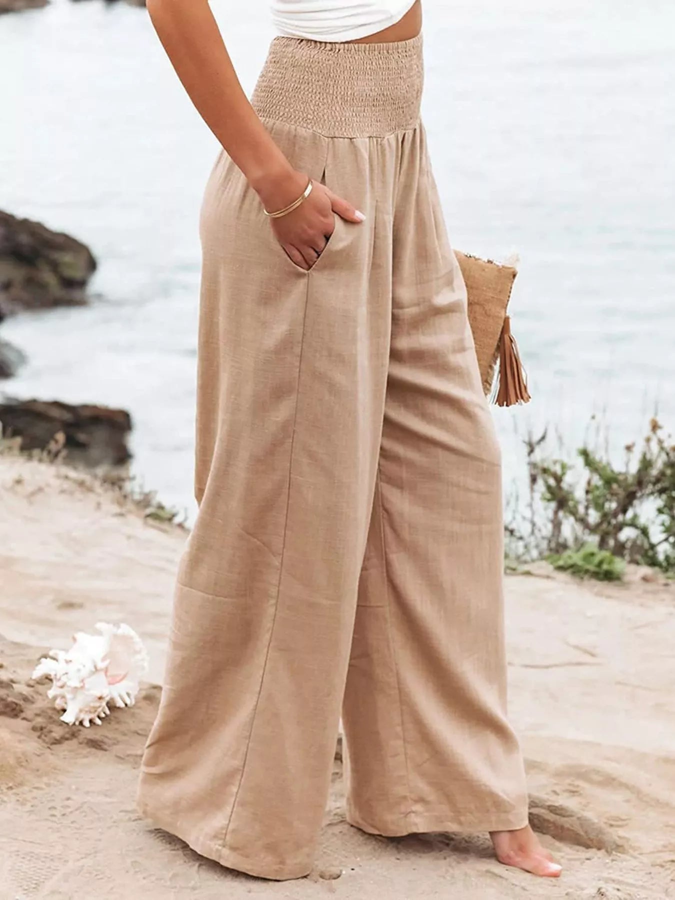 Person wearing beige wide-leg pants standing on a beach.