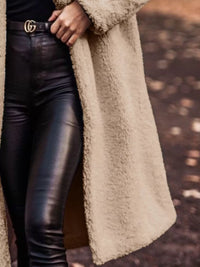 Person wearing a beige coat and black leather pants with a blurred background
