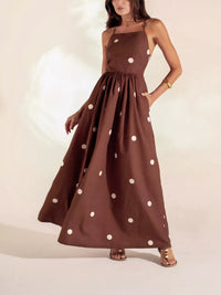 Brown dress with white polka dots worn by a model on a plain background