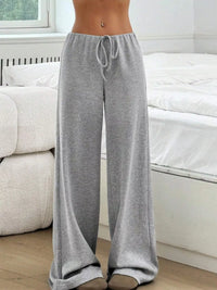 Person wearing gray drawstring pants in a room with white furniture.