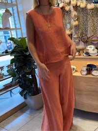 Person wearing an orange outfit in a store setting with decor and plants.