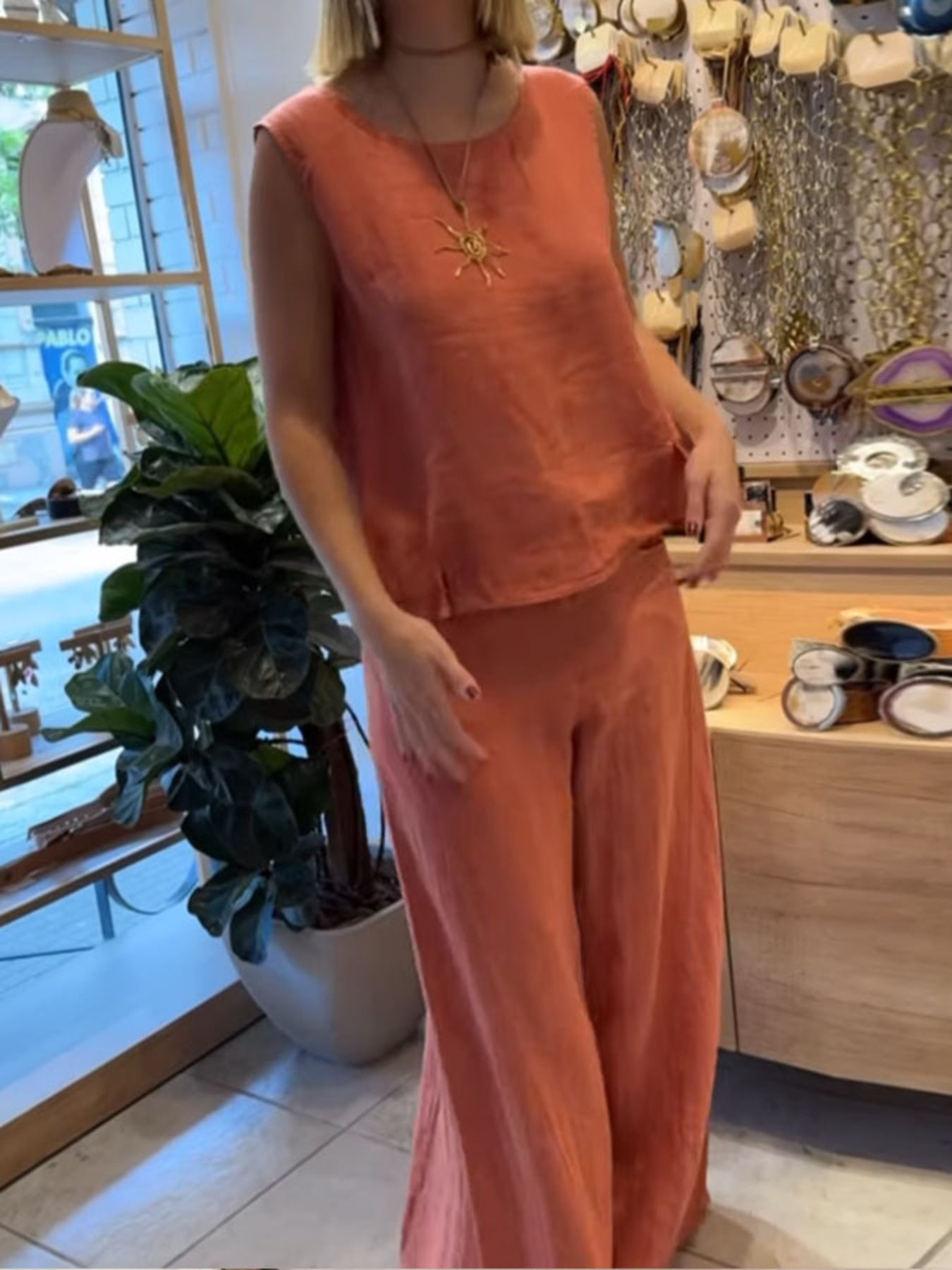Person wearing an orange outfit in a store setting with decor and plants.