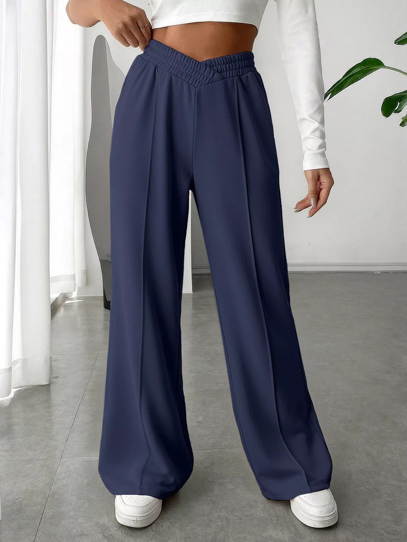 Person wearing navy wide-leg pants and white sneakers indoors.