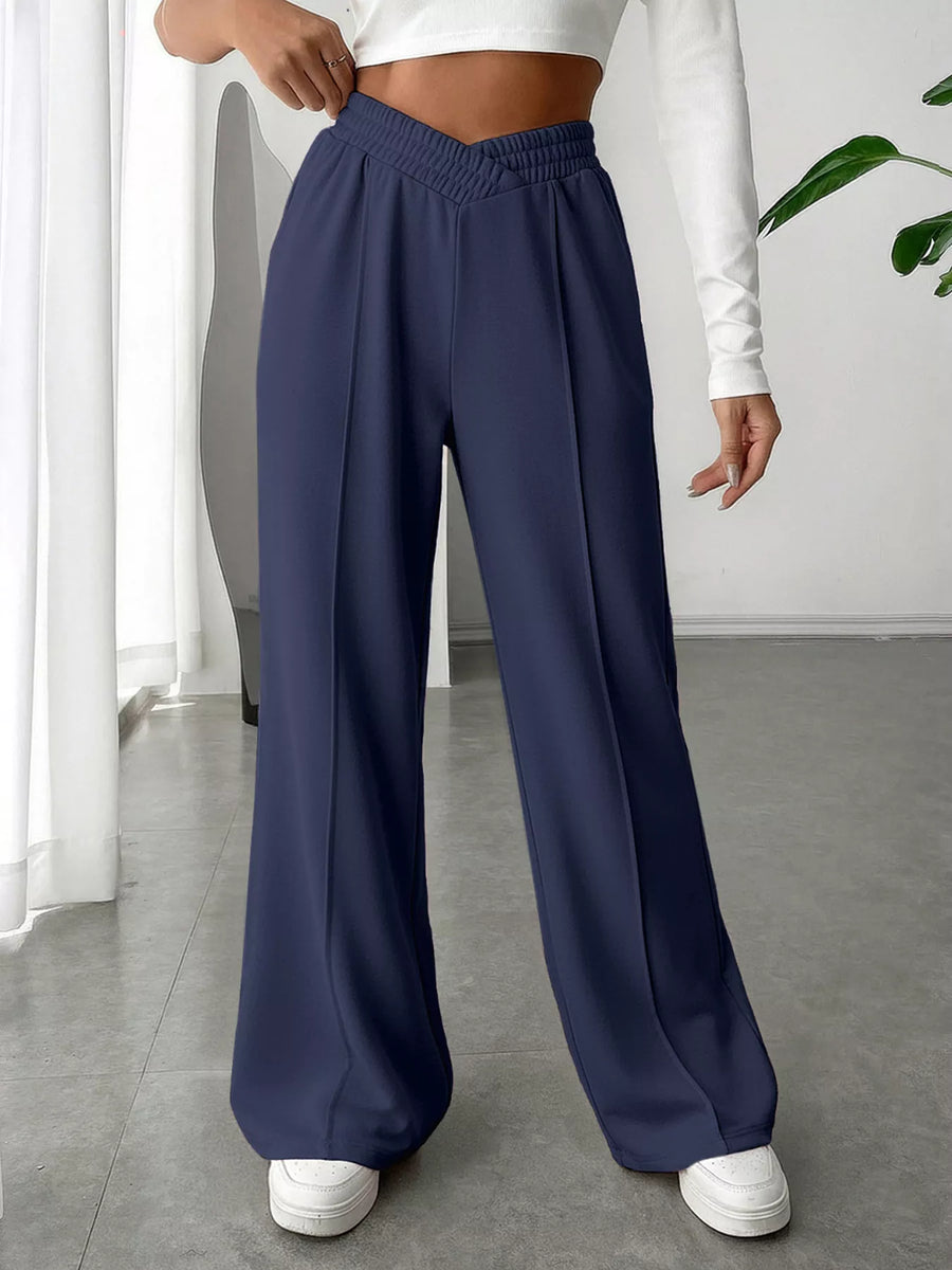 Person wearing navy wide-leg pants and white sneakers indoors.