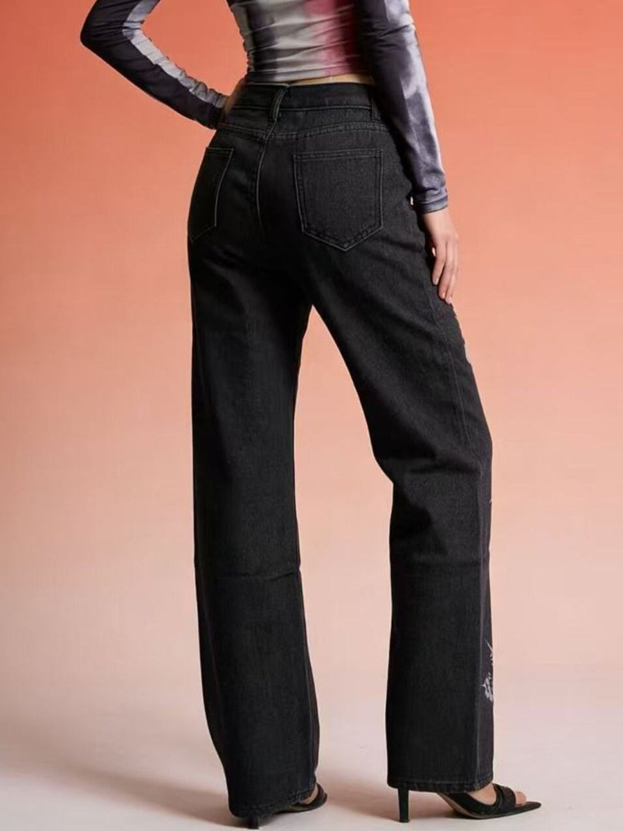 Person wearing black wide-leg jeans against a gradient background