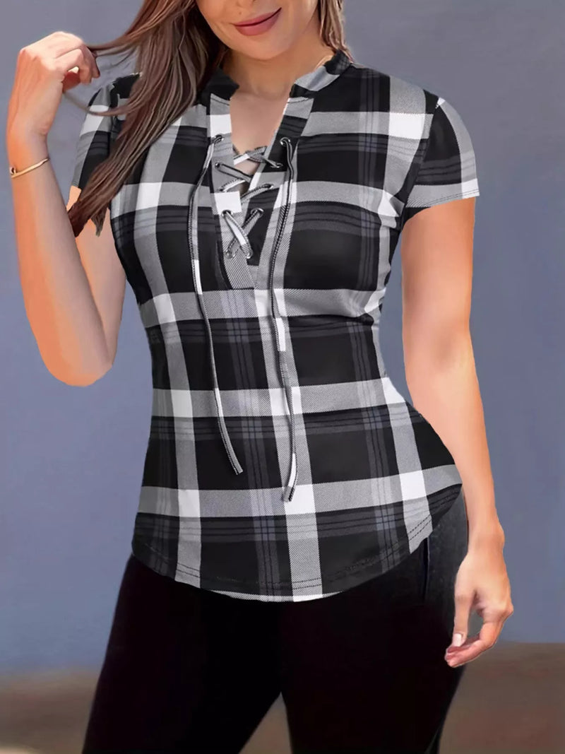 Woman wearing a black and white plaid shirt with a lace-up front against a gray background