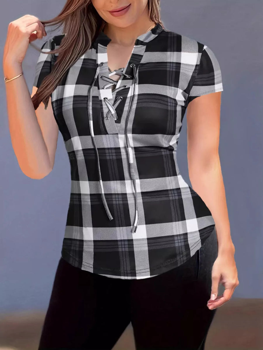 Woman wearing a black and white plaid shirt with a lace-up front against a gray background