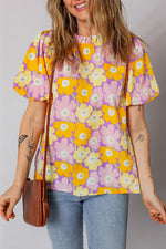 Woman wearing a colorful floral blouse with a plain background