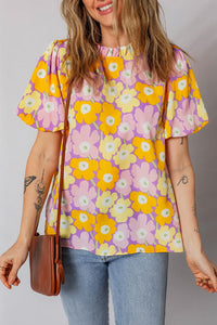 Woman wearing a colorful floral blouse with a plain background