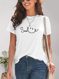Woman wearing a white t-shirt with 'Smile' text and smiley face, standing against a neutral background.