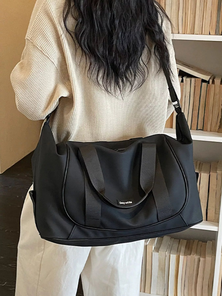 Person holding a black handbag in a room with bookshelves.