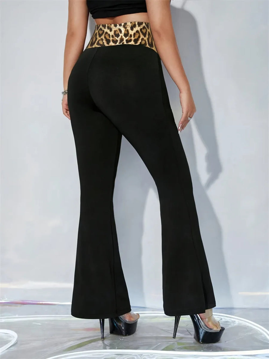 Person wearing black flared pants with a leopard print belt on a white background