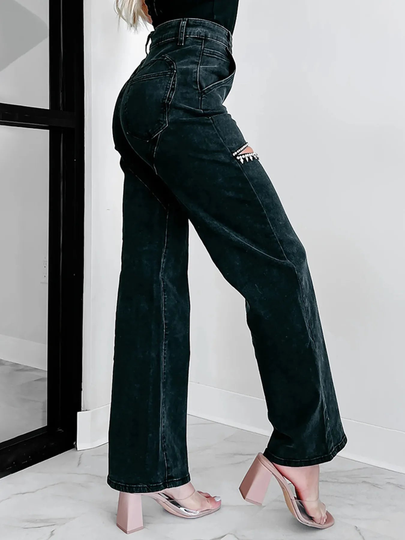 Person wearing black high-waisted jeans with a white background