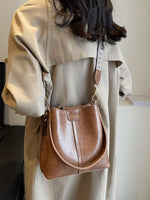 Person wearing a beige coat with a brown leather handbag.