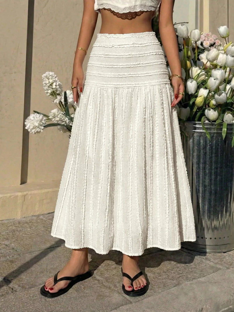 Person wearing a white lace top and skirt standing between two flower pots.