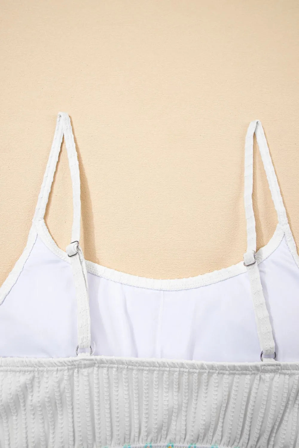 White spaghetti strap top on a beige background