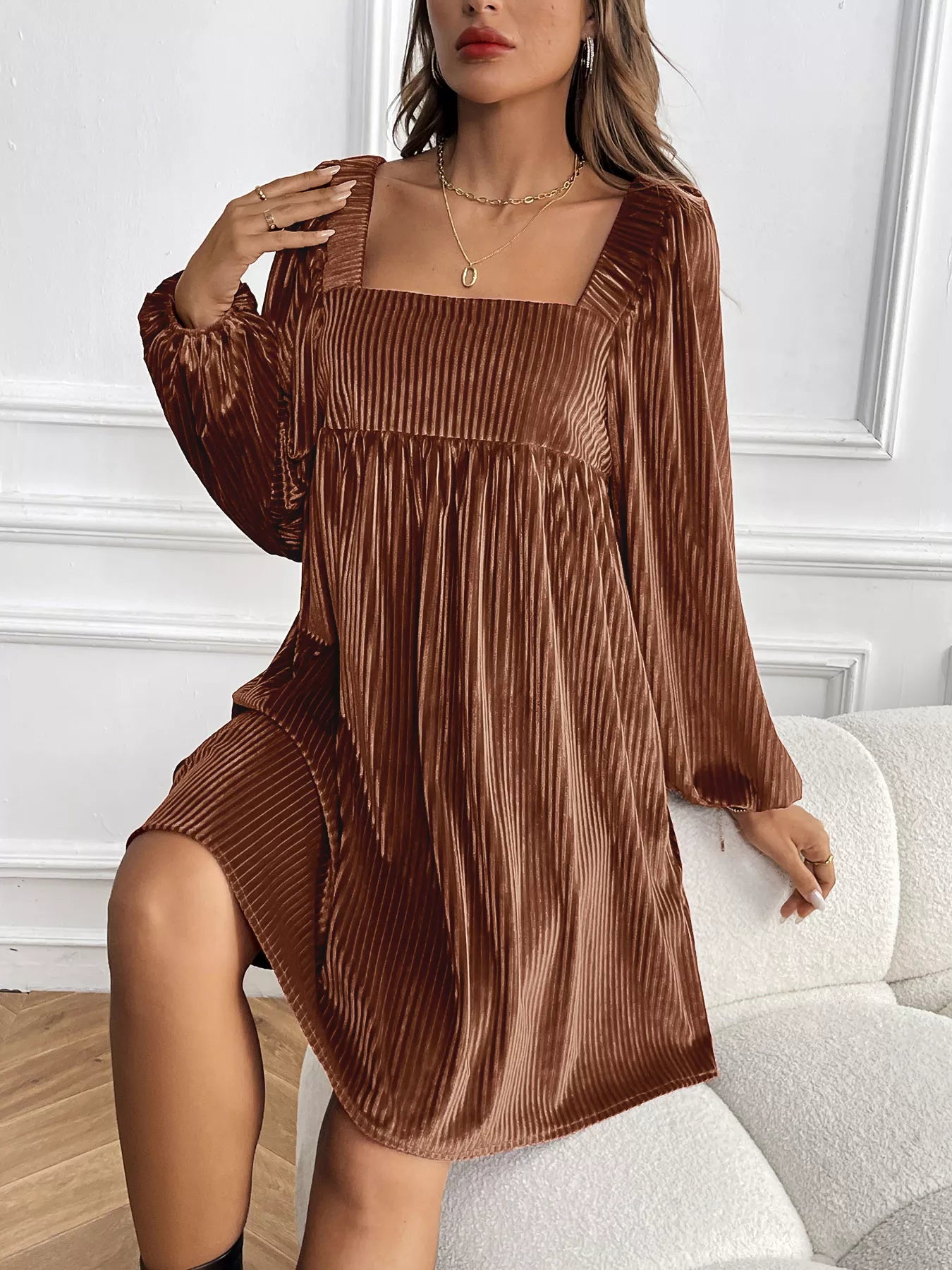 Woman wearing a brown pleated dress in an indoor setting