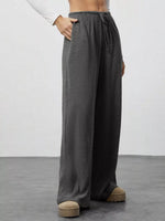 Person wearing gray wide-leg pants on a plain background