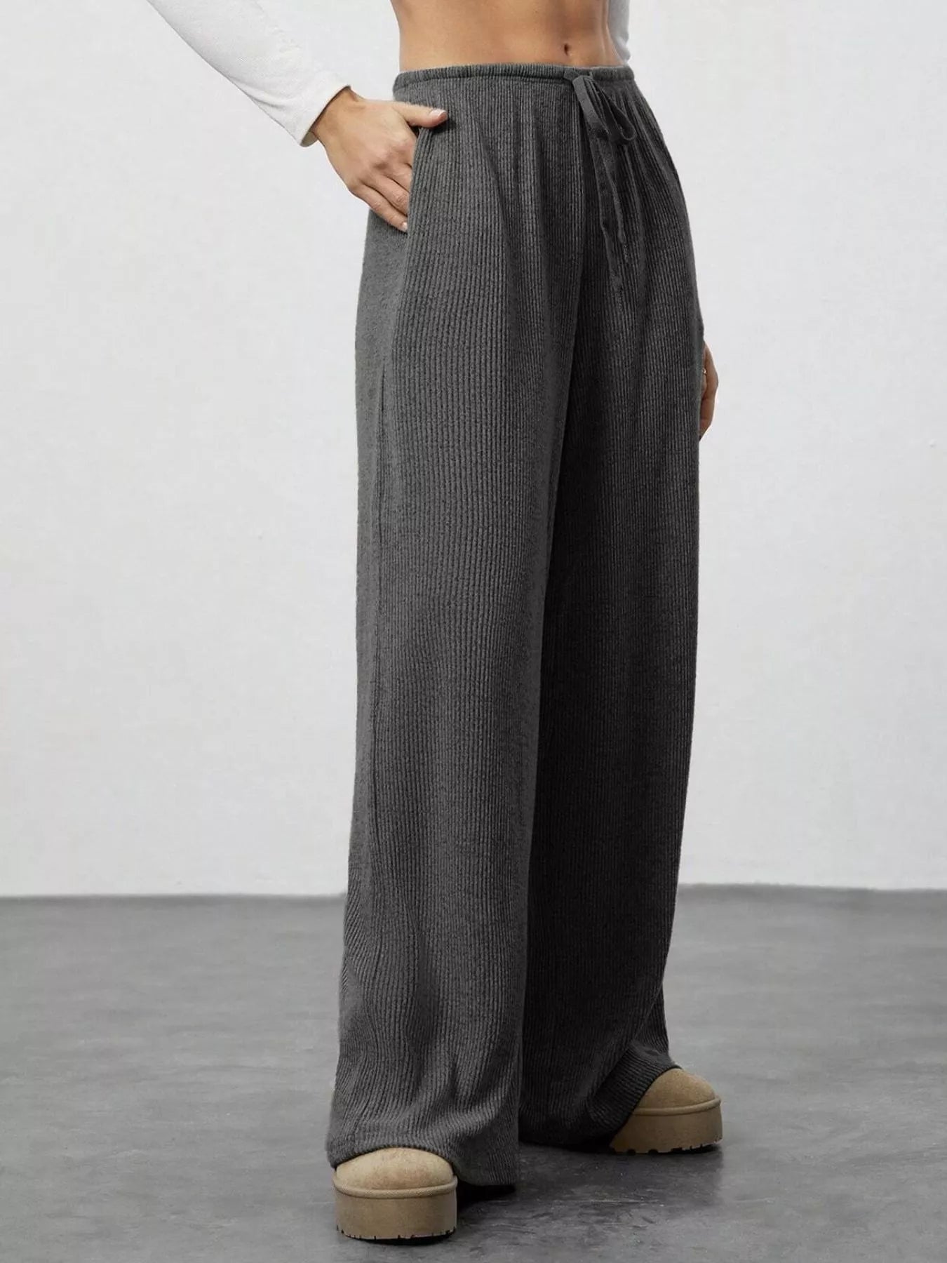 Person wearing gray wide-leg pants on a plain background