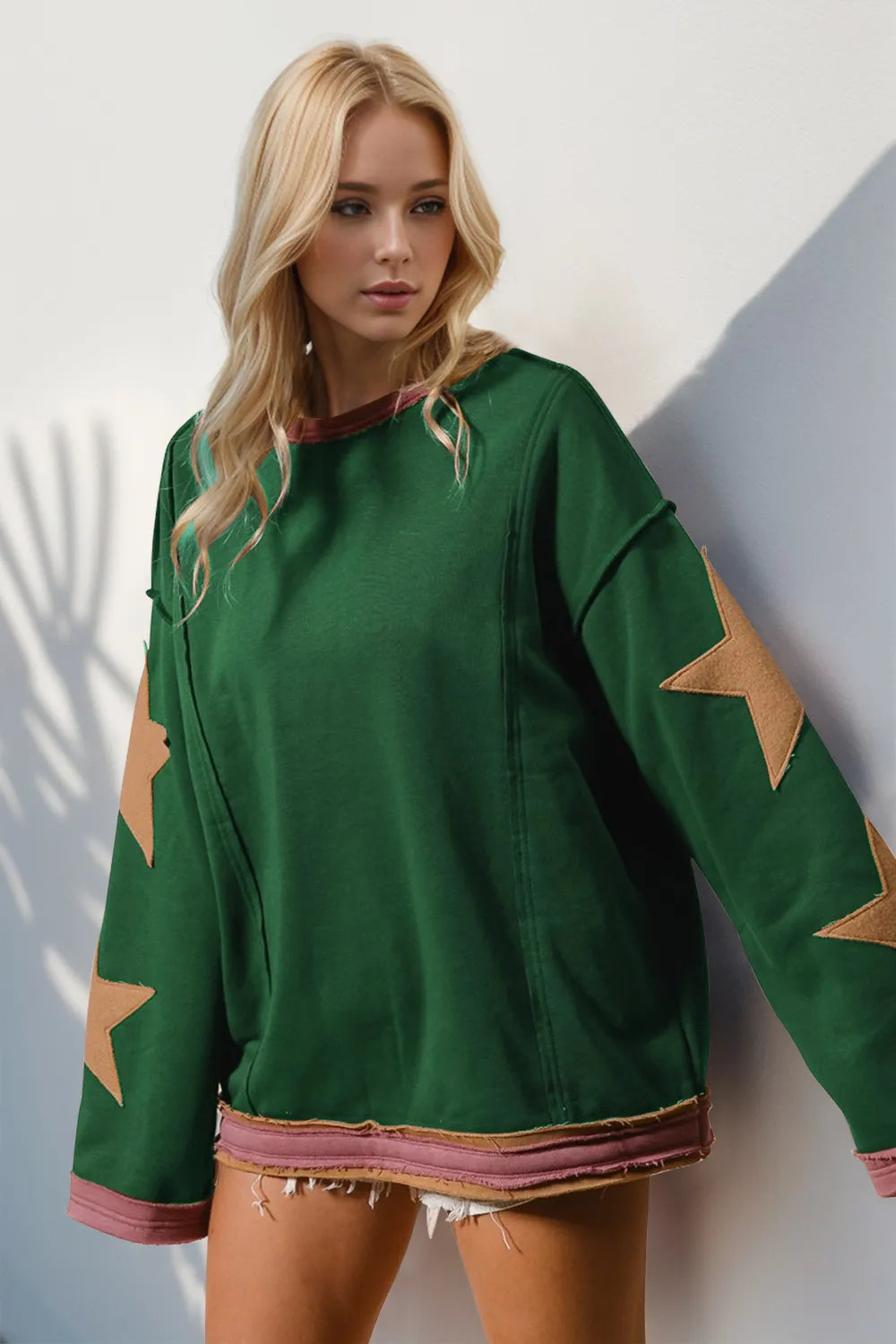 Woman wearing a green sweater with star patterns against a white wall