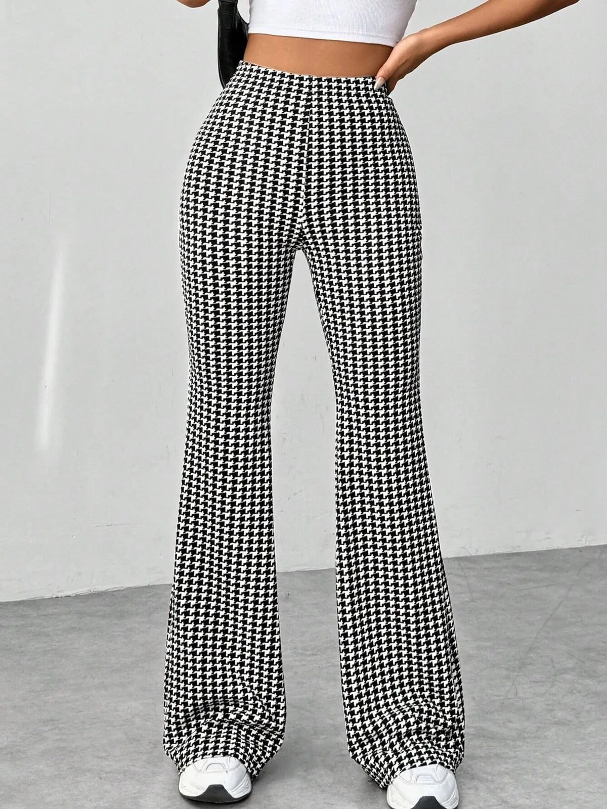 Houndstooth patterned pants worn by a person on a plain background