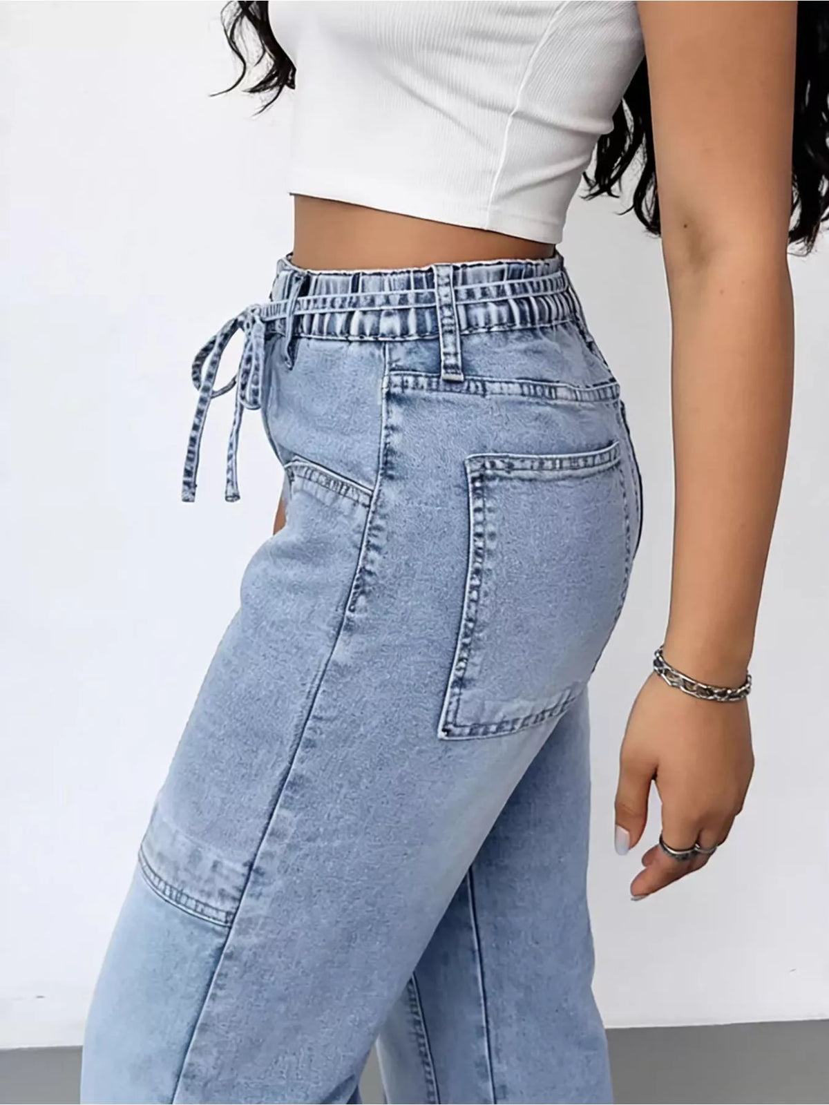 Light blue jeans with a tie-waist design worn by a person on a white background