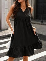 Woman wearing a black sleeveless dress on a city street.