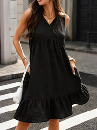 Woman wearing a black sleeveless dress on a city street.