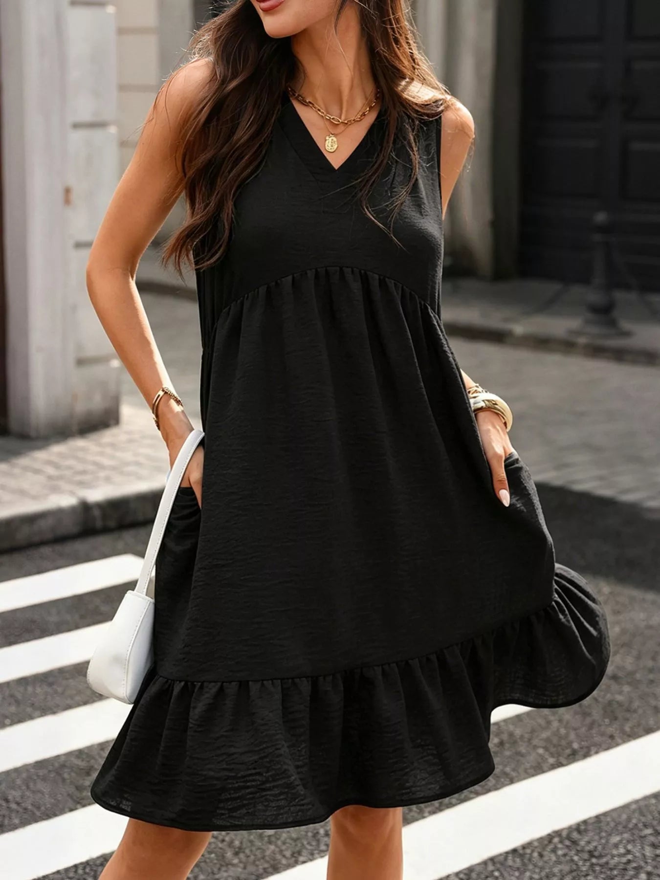 Woman wearing a black sleeveless dress on a city street.