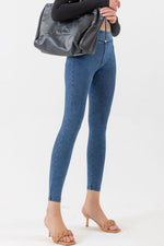 Person wearing blue jeans and holding a gray bag on a white background