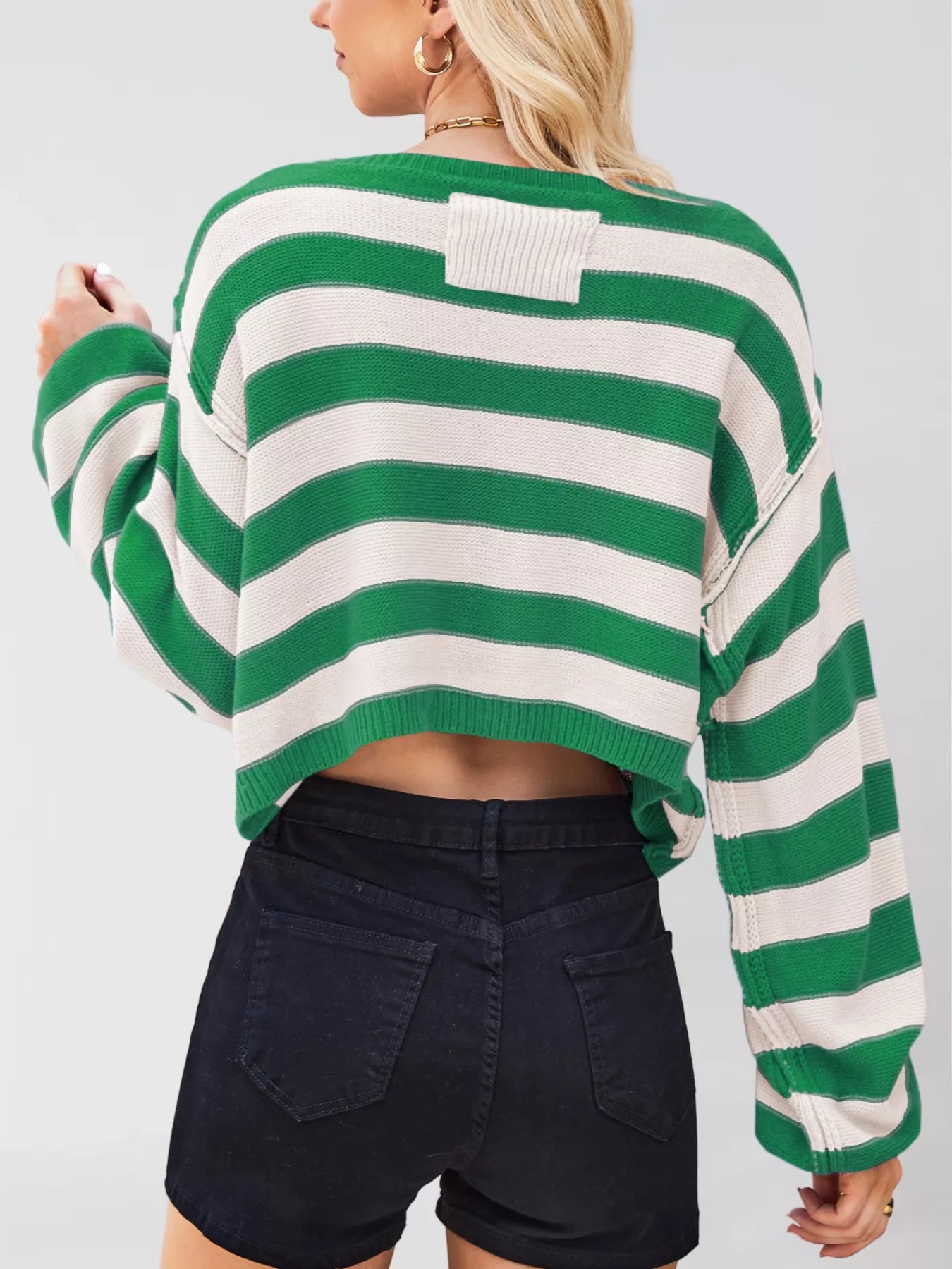 Green and white striped sweater worn by a person on a plain background