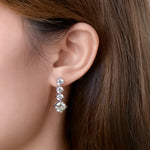 Close-up of an ear wearing a set of diamond earrings with a blurred background.