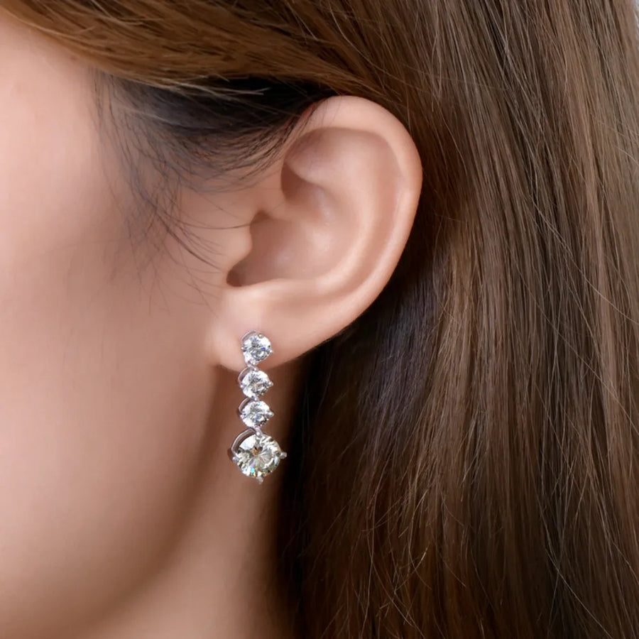 Close-up of an ear wearing a set of diamond earrings with a blurred background.