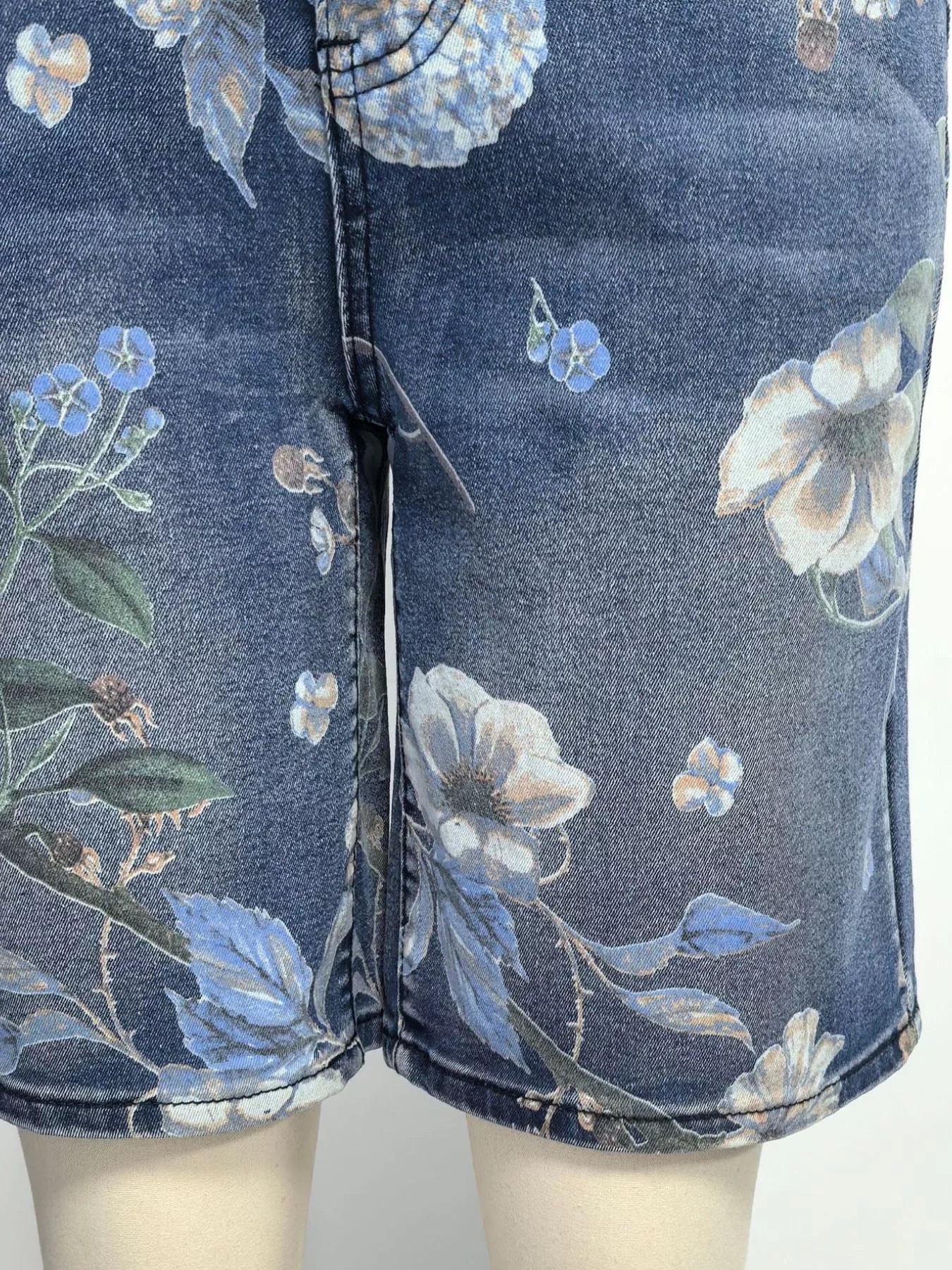 Denim shorts with floral pattern on a mannequin against a white background