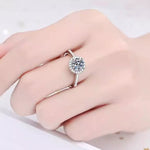 Silver ring with a large diamond on a hand against a white background