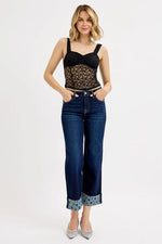 Woman wearing a black lace top and blue jeans on a white background