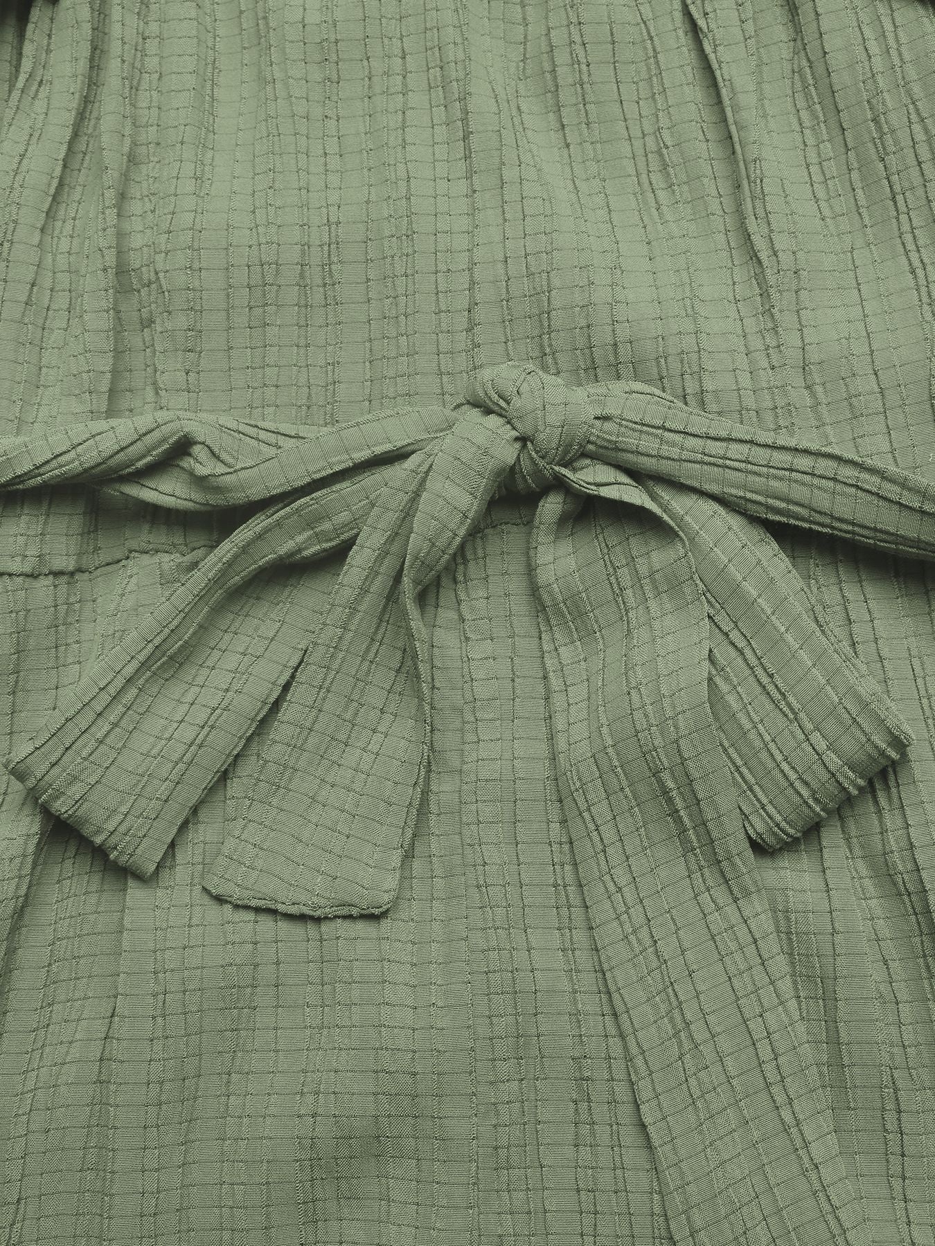 Close-up of a green textured garment with a tie detail.
