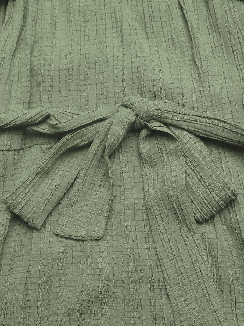 Close-up of a green textured garment with a tie detail.