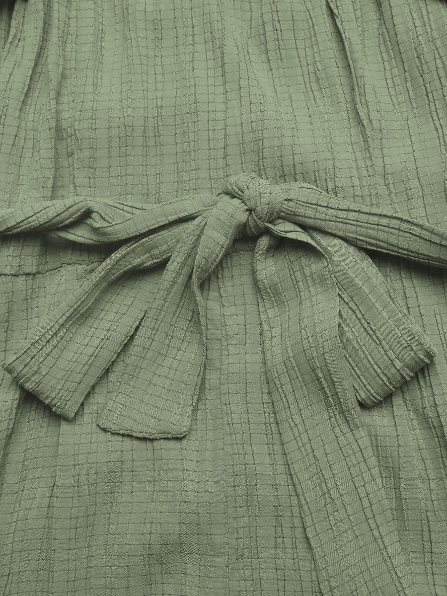 Close-up of a green textured garment with a tie detail.