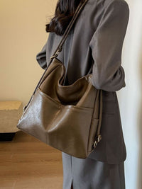 Person wearing a brown leather handbag in an indoor setting