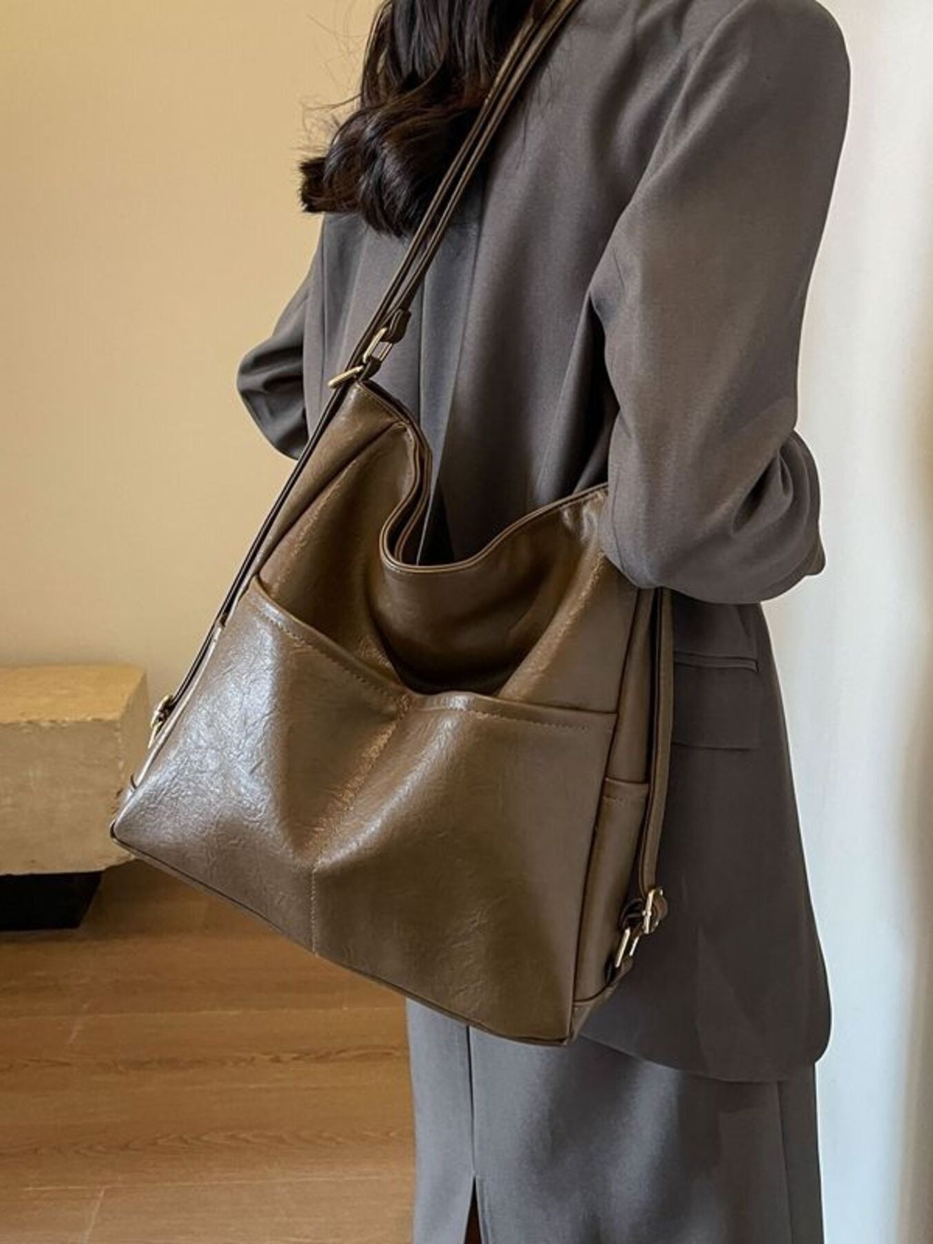 Person wearing a brown leather handbag in an indoor setting