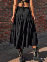 Person wearing a black tiered skirt and cowboy boots against a brick wall.