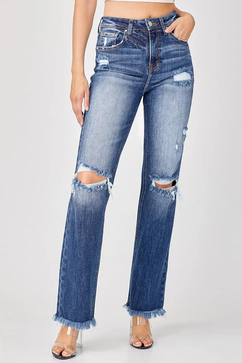 Distressed blue jeans worn by a person on a white background