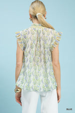 Woman wearing a floral blouse with ruffled sleeves against a light blue background