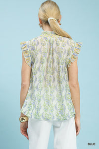 Woman wearing a floral blouse with ruffled sleeves against a light blue background