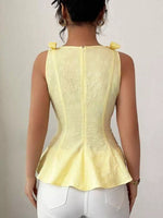 Person wearing a yellow sleeveless top with a plain background